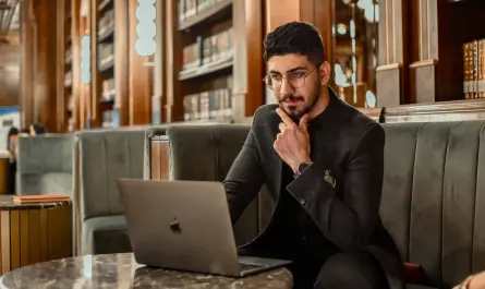 manager réfléchissant à son ordinateur dans une bibliothèque, symbolisant le leadership éthique