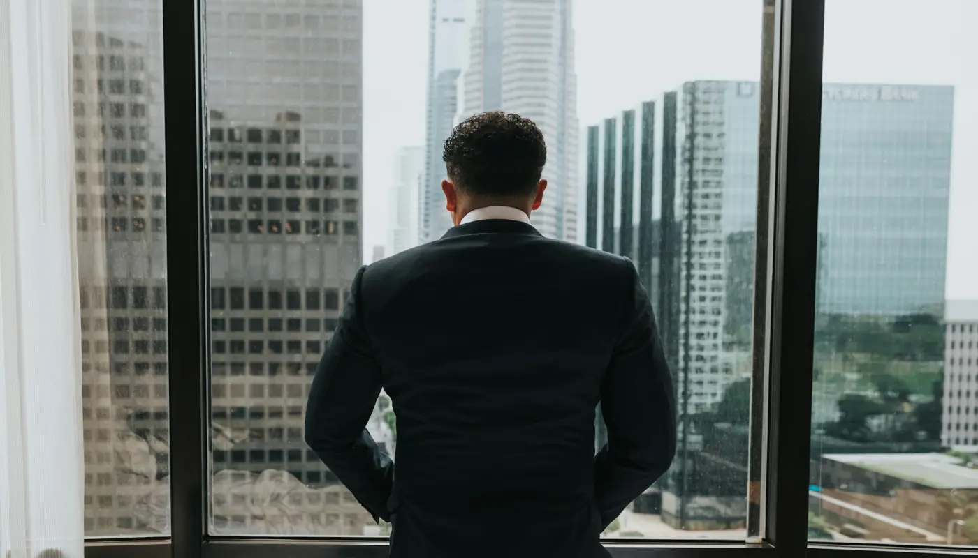 manager en costume regardant par la fenêtre vers les immeubles de bureaux d'une ville