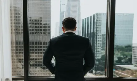 manager en costume regardant par la fenêtre vers les immeubles de bureaux d'une ville