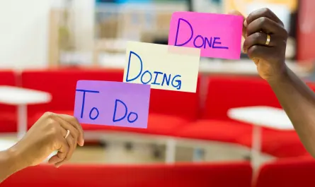 deux mains tenant des post-its colorés affichant "to do", "doing" et "done" illustrant la productivité