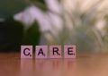 A wooden block spelling care on a table