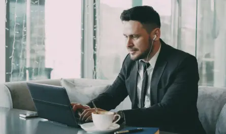 Business professional using a laptop in a cafe, wearing earbuds.